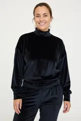 Buzo de cuello alto confeccionado en tela de terciopelo negro, de manga larga y corte holgado con puños y ruedo ajustados.