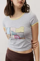 Remera corta gris melange con ribetes amarillos en el cuello y las mangas, y un estampado gráfico abstracto en el pecho.