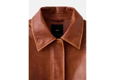 Chaqueta estilo aviador de cuero sintético en color marrón, con cuello y solapas de corderito sintético en color blanco. Presenta cierre frontal de cremallera, bolsillos frontales con solapa, puños y dobladillo de canalé elástico.