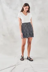 Minifalda negra con bordado blanco de motivos geométricos y terminación festoneada.