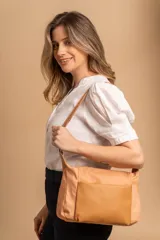 Bandolera de diseño práctico con combinación de texturas en tonos tierra, confeccionada en tela y símil cuero. Cuenta con un compartimento principal con cierre, un bolsillo frontal con cierre y correa ajustable para llevar al hombro o cruzada.