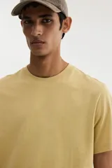 Remera de algodón de corte estándar, con cuello redondo y mangas cortas, en color mostaza.