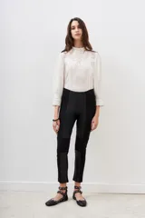Pantalon negro de corte ajustado, confeccionado en una combinación de materiales que incluye paneles de efecto cuero en la parte frontal y laterales, con diseño de costuras horizontales en las rodillas.