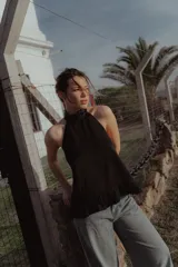 Top negro sin mangas con cuello halter bordado en lentejuelas, espalda descubierta y volado en el ruedo.