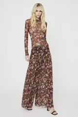 Pantalón ancho confeccionado en tul semitransparente, con estampado integral de alas de mariposa en tonos naranjas y negros, de tiro alto y diseño holgado.