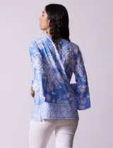 Blusa color salmón con estampado floral blanco, cuello redondo con abertura y mangas 3/4 acampanadas.