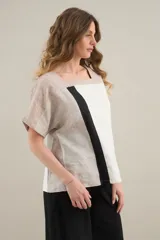 Blusa de lino de diseño contemporáneo, con escote cuadrado y mangas cortas en recortes que combinan distintas texturas. Su propuesta incorpora una franja vertical en contraste que aporta dinamismo y personalidad, mientras que el calce relajado la convierte en una prenda fresca y versátil.