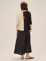 Buzo de tejido de punto bicolor con diseño dividido en negro y beige, cuello en V y mangas largas.