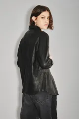 Camisa de cuero ovino color verde oliva, con cuello clásico, cierre frontal con botones y mangas largas con puños abotonados. Presenta un corte holgado y diseño tipo sobrecamisa.