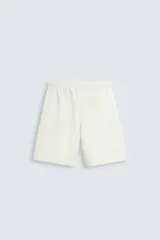 Bermuda de algodón color beige claro, corte relajado (relaxed fit), con cintura elástica ajustable mediante cordón y bolsillos laterales y trasero de plastrón.