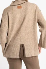 Polera oversize color beige melange, de punto con mangas largas y detalles de franjas marrones en las mangas y cuello.