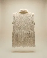 Chaleco tejido en lana merino, color negro, con cuello alto y diseño sin mangas. Presenta aplicaciones artesanales en relieve que simulan ovejas y un ruedo terminado con largos flecos.