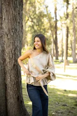 Blusa de lino con diseño asimétrico de un solo hombro, manga larga abullonada y detalle de lazo lateral en la cintura con volado.