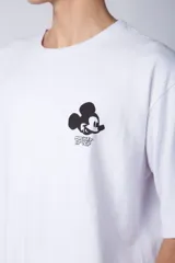 Remera negra de corte oversize confeccionada en algodón pesado, con estampa pequeña de Mickey Mouse en el pecho y diseño gráfico en la espalda.