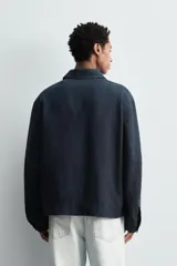 Cazadora regular fit color azul marino, confeccionada en tejido de lino con efecto ligeramente lavado. Presenta cuello solapa, manga larga con puño abotonado, bolsillos de vivo en la cadera y un bolsillo interior. Cierre frontal con cremallera.