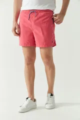 Short de baño liso con cintura elástica y cordón ajustable. Cuenta con dos bolsillos laterales, un bolsillo trasero y logo bordado en la parte inferior.