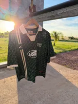 Camiseta tipo polo de Scuffers, color verde con estampado monograma y detalles en blanco en el cuello, los puños y los gráficos frontales de estilo deportivo vintage.