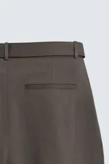 Pantalón de corte wide fit confeccionado en tejido con algodón. Presenta pliegues frontales, cintura ajustable con cinturón integrado, bolsillos laterales y bolsillos traseros de vivo. Cierre frontal con cremallera y botón.