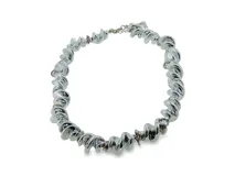 Collar de metal plateado con eslabones retorcidos y texturizados que forman una estructura entrelazada y dinámica.
