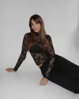 Polera de encaje negro con diseño floral, cuello alto y mangas largas.