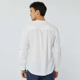 Camisa blanca de lino con cuello mao, manga larga con puños abotonados y bolsillo de parche en el pecho. Cierre frontal con botones a tono.