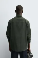 Camisa de corte regular fit confeccionada en tejido de algodón con textura de cuadrillé. Presenta cuello solapa, manga larga con puños abotonados y cierre frontal mediante botonadura.