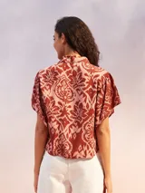 Camisa de manga corta con estampado de flores en tonos amarillo, negro y beige.