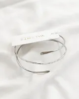 Brazalete rígido plateado de tres vueltas con terminaciones redondeadas.