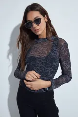 Body de mangas largas con cuello alto, confeccionado en tejido de tul semitransparente con estampado animal print en tonos grises y negros.