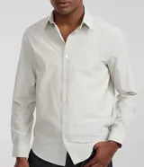 Camisa de sastrería rayada color celeste y blanca, de corte regular, con cuello solapa, cierre frontal de botones y manga larga.
