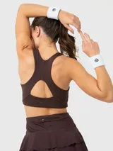 Top deportivo de color marrón chocolate, con escote redondo, espalda con tirante central grueso y sujetador integrado. Presenta un diseño minimalista con logo sutil en el pecho.