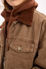 Campera de denim en tono marrón con diseño vintage, corte relajado, cuello de pana y bolsillos delanteros con solapa.