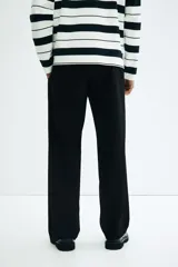 Pantalón negro de sarga de algodón, con cierre y botón, bolsillos al bies, bolsillo monedero oculto y bolsillos traseros insertados con botón. Corte relajado.