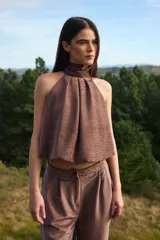 Blusa sin mangas de corte holgado con cuello alto tipo halter y pliegues frontales. Confeccionada en tela con textura sutil.