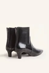 Botín blanco con estampado de piel de serpiente, punta fina y taco chupete. Cierre con cremallera en la parte trasera.