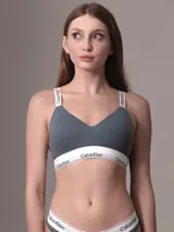 Bralette Calvin Klein de algodón elástico, color gris azulado, con copas ligeramente acolchadas y sin aros. Presenta banda elástica inferior con logo y tirantes ajustables con logo.