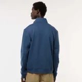 Buzo azul con cuello alto y cremallera parcial.