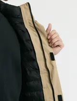 Campera 2 en 1 color beige, con cuerpo y capucha desmontable, manga larga, cierre frontal con botones a presión y bolsillos laterales engomados.