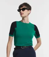 Blusa de viscosa con cuello redondo y mangas cortas. Presenta un diseño de bloques de color contrastantes, con cuerpo en tono malva y mangas en color negro, destacando por sus recortes asimétricos en la sisa.
