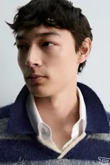 Polo de punto cepillado con diseño de rayas horizontales en azul marino y gris. Presenta cuello solapa con abertura frontal, manga larga y texto bordado en el pecho. Acabados en rib en puños y ruedo.