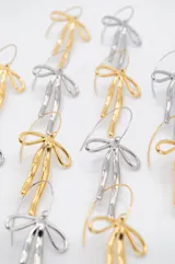 Aros colgantes dorados con forma de moño irregular.