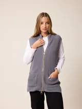 Chaleco de tejido de punto en color gris, con cierre frontal completo, cuello alto y dos bolsillos delanteros tipo parche.