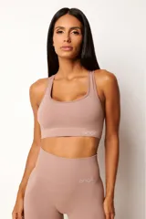 Conjunto deportivo de top nadador y calza larga de tiro alto en color tostado, confeccionado en tejido seamless con textura acanalada y efecto modelador.