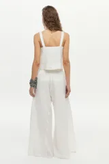 Pantalón palazzo de lino color blanco, de corte amplio con aberturas laterales, cintura elastizada con lazo ajustable y bolsillos.