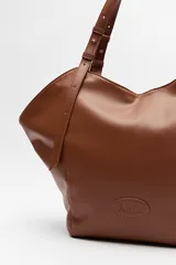 Bolso negro tipo tote de cuero sintético con acabado soft touch, asas largas regulables y diseño minimalista.