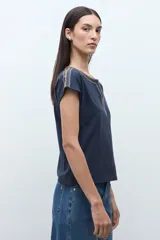 Remera blanca de algodón con escote en V y detalles de bordado étnico en tonos rojizos y naranjas en el cuello y los hombros. De corte recto y manga corta.