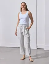 Pantalón de lino color beige con rayas verticales blancas, pretina elastizada con cordón ajustable, bolsillos laterales y ruedo con botamanga.