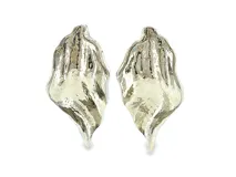 Pendientes en metal plateado con diseño escultórico, textura ondulada y orgánica, de forma asimétrica y fluida.