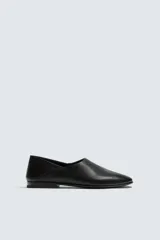 Mocasín de piel color negro, con diseño minimalista de parte superior lisa, horma ligeramente cuadrada y suela ultrafina.