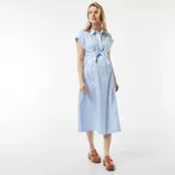 Vestido camisero de maternidad midi, color azul claro con rayas verticales blancas. Presenta cuello camisero, botones frontales, mangas cortas y un lazo anudable en la cintura.